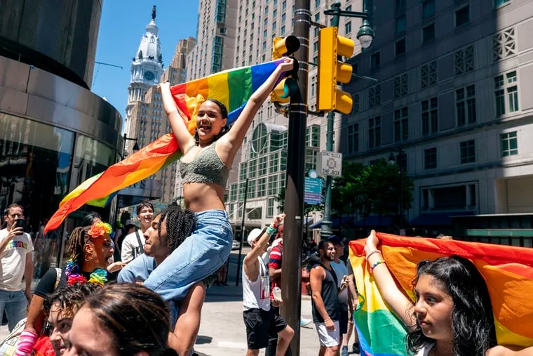 Kimberly Orozco rides on the shoulders of Keven Collins as they march up Market Street during Pride celebrations in June, 2022.