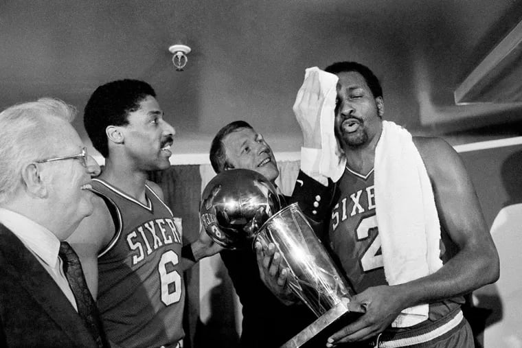 Philadelphia 76ers coach Billy Cunningham wiped the victorious brow of Moses Malone, holding the team's NBA World Championship trophy after the winning game against the Los Angeles Lakers in Los Angeles, on June 1, 1983. To the left is Julius Erving (6).