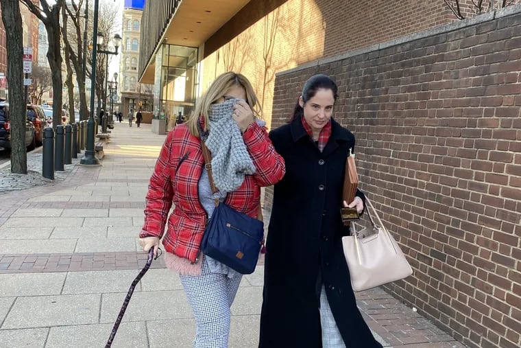 Ana Molina (left) covers her face with a scarf as she leaves federal court with her defense lawyer, Caroline Goldner Cinquanto. She pleaded guilty in an immigration fraud scheme.