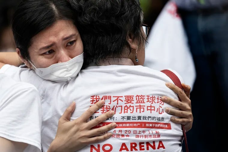 Chinatown residents Debbie Law, left, and Debbie Wei, embrace during a “no Sixers arena rally” outside Philadelphia City Hall.