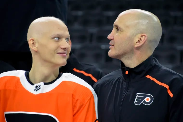 Oskar Lindblom (left), who is undergoing cancer treatments, with assistant coach Ian Laperriere at the Flyers' team photo session Monday.