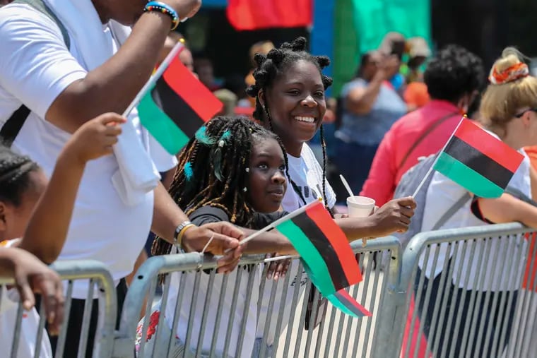 Alanna Bynes, 10, and her mom Alicia Jeremiah, of West Philly, wave flags and watch the Philadelphia Juneteenth Parade and Festival in West Philadelphia, Pa. on Sunday, June 18, 2023. The first Philadelphia Juneteenth Parade and Festival was in 2016. Juneteenth commemorates the end of slavery in the United States. In 2021 President Joe Biden named Juneteenth, celebrated on June 19, a federal holiday.