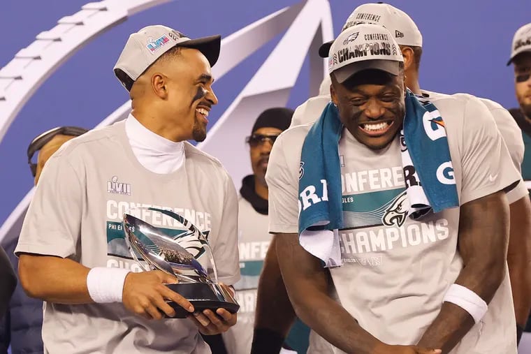 Eagles quarterback Jalen Hurts holds the NFC Championship trophy with teammate wide receiver A.J. Brown.