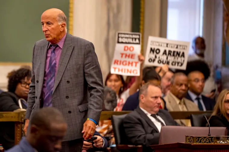 In this 2023 file photo, Councilmember Mark Squilla is on the floor in City Council chambers as protest signs are held behind him related to the proposed Sixers arena.