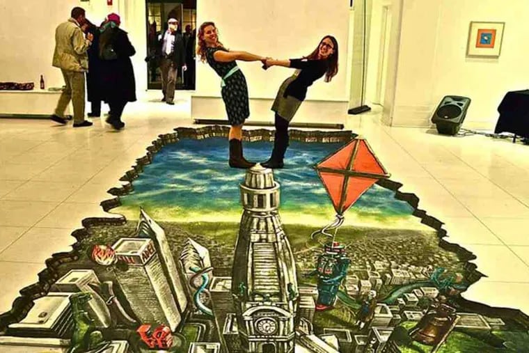 Science Festival director Gerri Trooskin (right) and festival coordinator Josette Hammerstone (left) ham it up while standing atop 3D street art that will be at the Logan Circle carnival tomorrow.