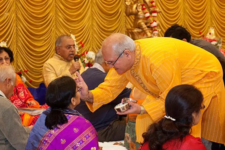 Ghanshyam Dave applies the tikka symbol to a woman at Sunday's ceremony . ED HILLE / Staff Photographer
