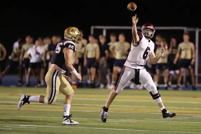 Kyle McCord of St. Joseph's Prep rolls out to pass under pressure from Timothy Barrett of La Salle during the Philadelphia Catholic League football clash between the two old rivals on Sept. 28, 2019.