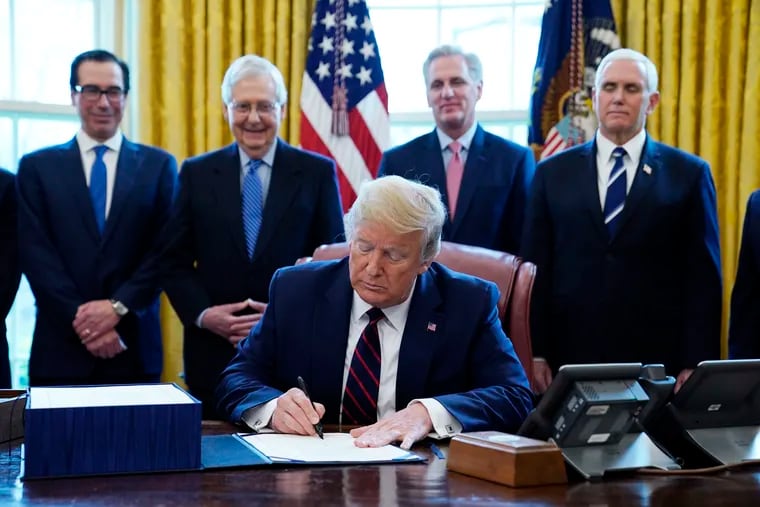 President Donald Trump signs the coronavirus stimulus relief package, at the White House, Friday, March 27, 2020, in Washington, as from left, Treasury Secretary Steven Mnuchin, Senate Majority Leader Mitch McConnell of Ky., House Minority Kevin McCarthy of Calif., and Vice President Mike Pence, look on.