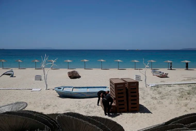 Workers arranged sunbeds as others install umbrellas at Plaka beach on the Aegean island of Naxos, Greece, on May 12.