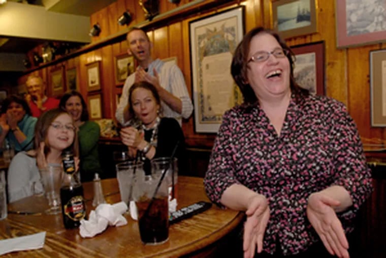 Celeste DiNucci (right) applauds as she and friends watch her appearance at a local pub.