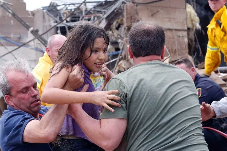 A child is pulled from the rubble of the school and passed along to a chain of rescuers.