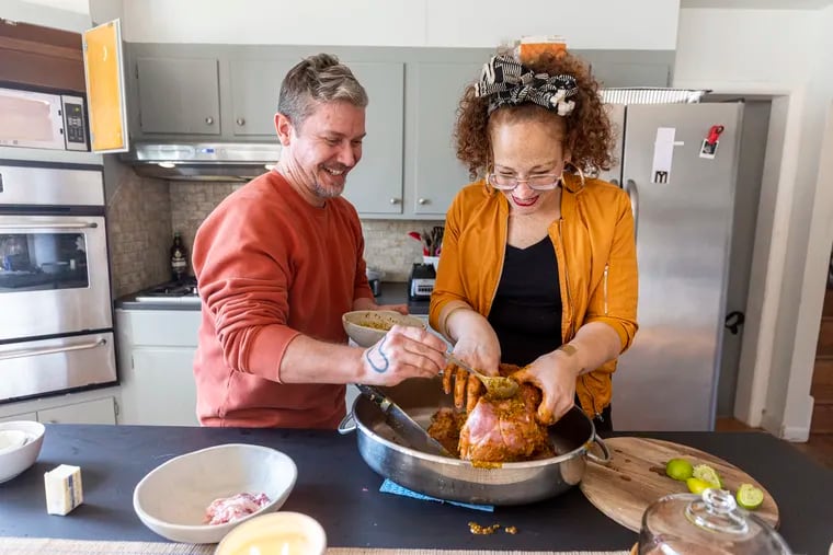 Nasheli Ortiz Gonzalez, 42, of Caguas, Puerto Rico, (right), and her boyfriend Quintin Rivera Tor, 45, (left), add the Sofrito to the holes and rubbed into the meat of the pernil in Philadelphia, Pa., on Wednesday, Dec. 13, 2023.