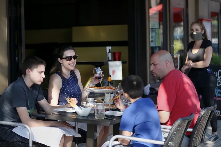 Melanie Santiago of Roxborough (second from left), her husband, Ricky (right), and their sons, Cole (left), 12, and Quinn (second from right), 9, eat pizza outside Jake's and Cooper's Wine Bar on Main Street in Philadelphia's Manayunk section on Friday, June 12, 2020. The city allowed outdoor dining to resume Friday for the first time since the city's coronavirus shutdown.