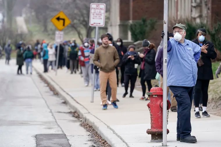 In this April 7 file photo, voters observe social distancing guidelines as they wait in line to cast ballots in the presidential primary election in Milwaukee.
