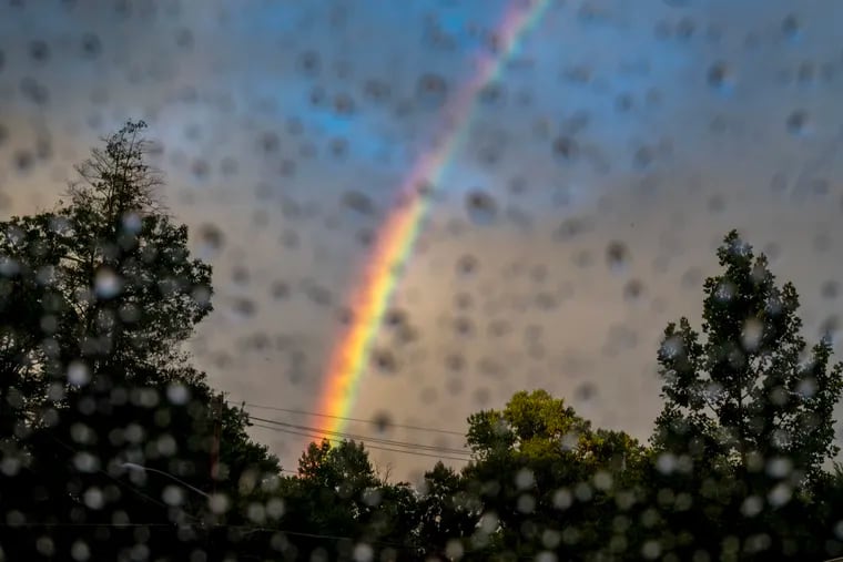 A natural spectrum - sunlight refracting in raindrops in the air - is photographed through other droplets on a car windshield in Haddonfield, Saturday evening as it was a banner night for rainbow sightings.