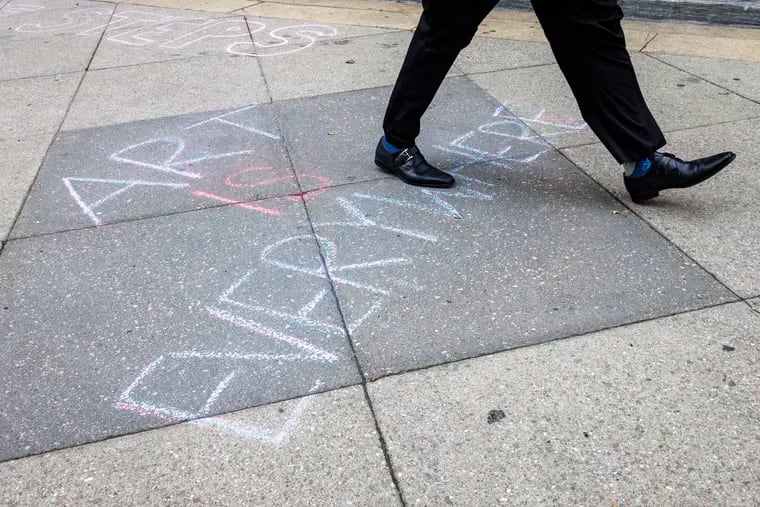 Art is Everywhere is written with chalk on the sidewalk outside the University of the Arts at S. Broad Street and Pine. Students gathered on campus protesting the closure of their school.
