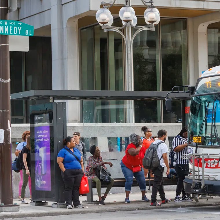 Commuters waiting at bus stop along JFK Boulevard at 15th Street in front of the Municipal Services Building in Center City.