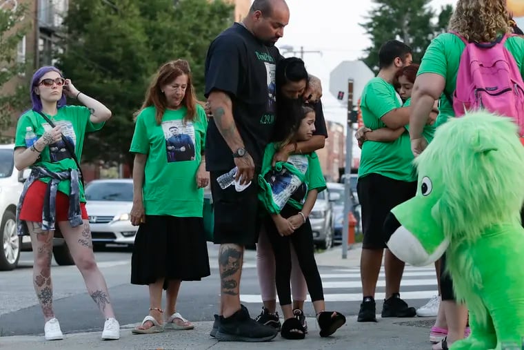 David Padro, in black shirt, embraces family during a vigil Sunday for his son David Padro Jr., who was killed outside Pat’s Steaks in South Philadelphia.  Friends and family gathered for a vigil there.  A Reading man is charged with murder.