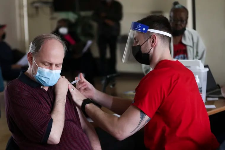 Gordon Palmer receives a dose of the Johnson & Johnson COVID-19 vaccine from Josh Redlich, a nursing student at Rutgers, at the Mickle Towers housing complex in Camden in April. Officials are seeing a small but concerning rise in a virus variant that can be stopped by full vaccination.