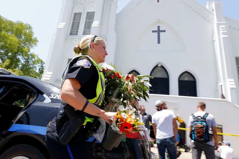 Charleston Police Officer T. Graves carries flowers to a memorial at the Emanuel A.M.E. Church. The attacker sat through a Bible study session before opening fire, authorities say.
