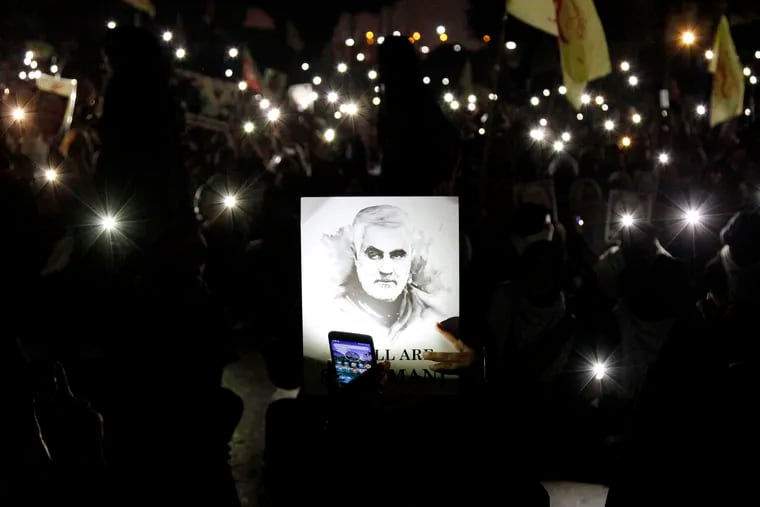 A Shiite Muslim illuminates a portrait of Iranian Revolutionary Guard Gen. Qassem Soleimani, with light from a mobile phone, during a rally to condemn his killing in Iraq by a U.S. airstrike, in Karachi, Pakistan, Sunday, Jan. 5, 2020. Iran has vowed "harsh retaliation" for the U.S. airstrike near Baghdad's airport that killed Tehran's top general and the architect of its interventions across the Middle East, as tensions soared in the wake of the targeted killing.