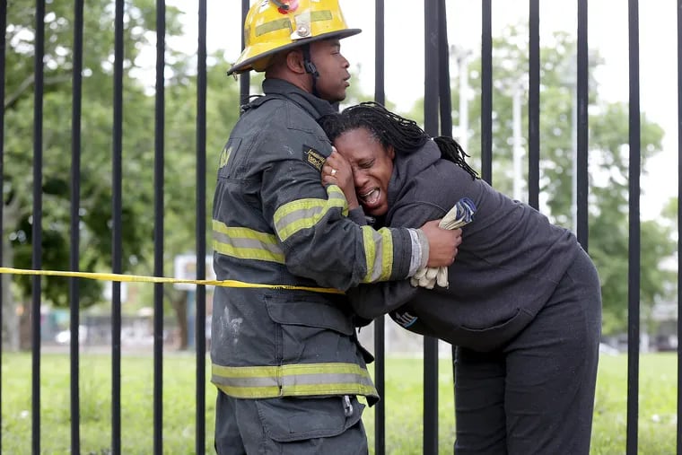 A firefighter comforts an unidentified family member at the scene of a fatal building collapse at Bailey and Jefferson Streets in North Philadelphia, on June 4, 2018. 