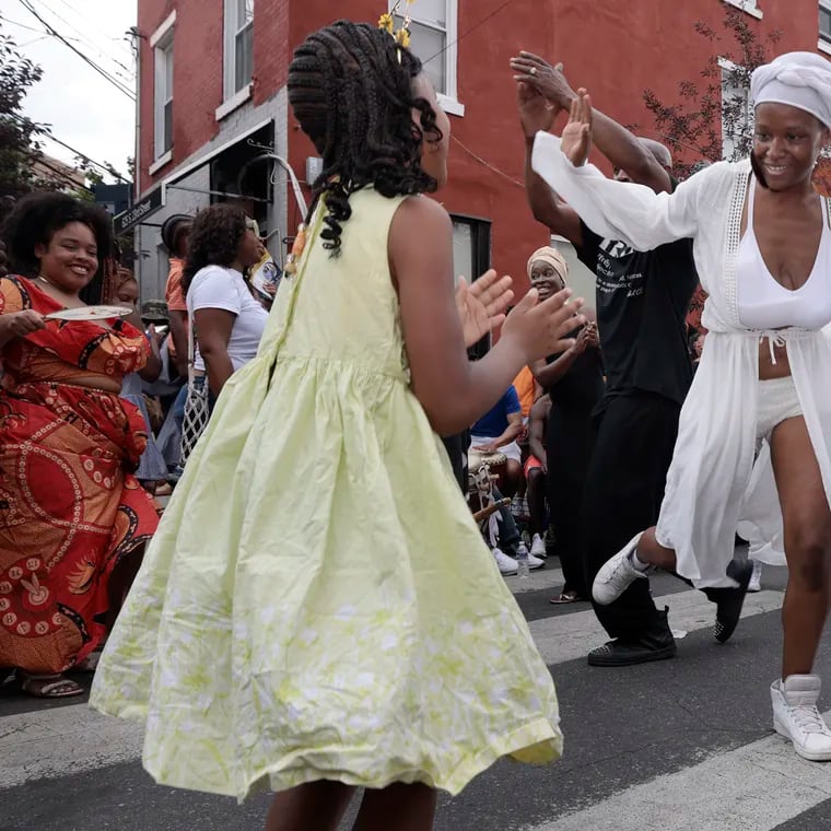 Sanchel Brown and Nubienne Productions of Phila. (right) gets 6 year old Riley Peterson (left) involved as she demonstrates traditional West African dance at the Odunde Festival on South St.