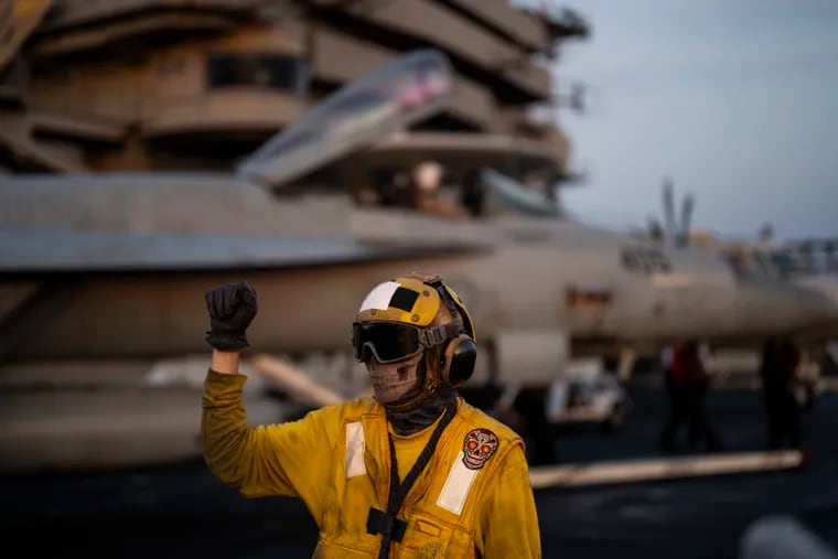 An air traffic controller directs a plane on the flight deck of the USS Dwight D. Eisenhower in the Red Sea on June 11.