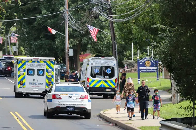 Kids are escorted by police away from the scene of what authorities described as a standoff with a man inside an apartment in the area of the Yardley Commons Condominium Complex on Wednesday. The Yardley police chief was shot in a standoff that ended hours later.