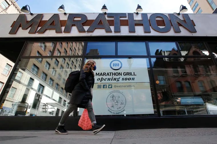 A pedestrian passes Marathon Grill. The restaurant was heavily damaged during the unrest last spring and will reopen on March 23.