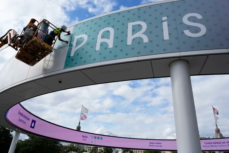 A worker puts on the finishing touches on a sign outside a venue ahead of the start of the Olympics in Paris.