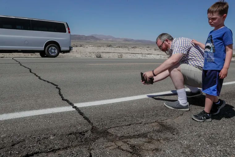 Andy Randolph and his son William stop for photos of a crack in California State Route 178 hours after a 6.4 magnitude earthquake struck the Searles Valley area in southern California on Thursday, July 4, 2019.