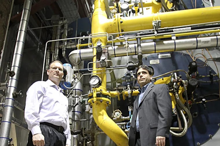 Veolia Energy executives Peter Quirk (left) and Michael Smedley stand before one of the company’s new rapid-start natural-gas-fired boilers at the Grays Ferry plant.  CHARLES FOX / Staff Photographer