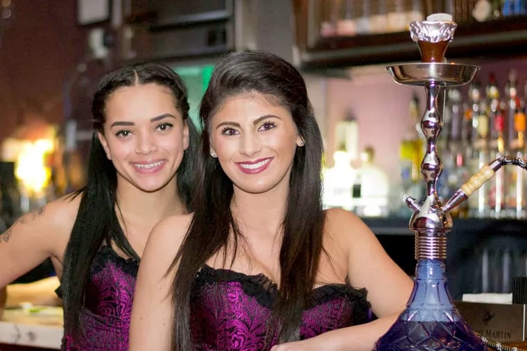 Employees Chelsea Reed and Marina Andaloro serve drinks and prepare hookah pipes for customers at Infusion Lounge.