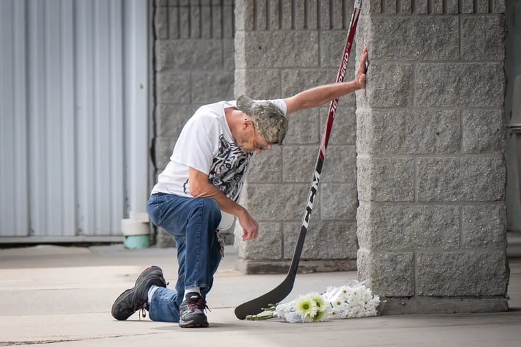 A former employee of the Hollydell Ice Arena stops to pray at a memorial for Johnny and Matty Gaudreau, who were tragically killed Thursday night.