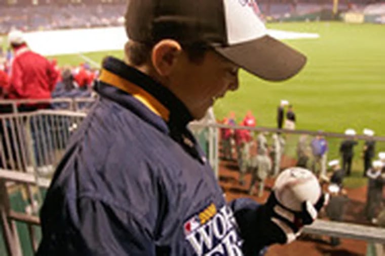 Jack Russell, 8, checks out a Cole Hamels-signed baseball. The game started late after day of steady rain and whipping winds.