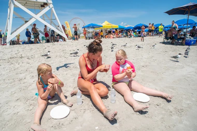 Veronica Praweckyj, 6, lifeguard Grace Comas, 17, and Sage Praweckyj, 8, have lunch during the 11th annual 21 Down Beach Day in Wildwood, N.J., in 2019.