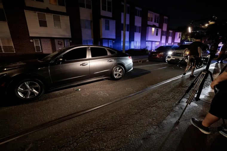 Cameramen film a car that was shot up on North 12th Street, near Fairmount, in Philadelphia on Friday.