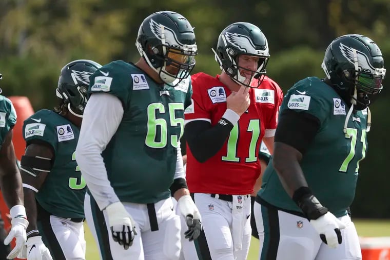 Eagles quarterback Carson Wentz (11) prepares to run a drill next to Lane Johnson (65) and Jason Peters (71) during practice at the NovaCare Complex in South Philadelphia on Friday, Aug. 21, 2020.