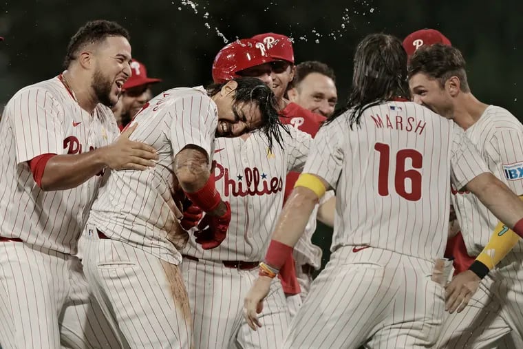 Nick Castellanos (second from left) is mobbed by teammates after he drove in the winning run with an 11th-inning single against the Braves.