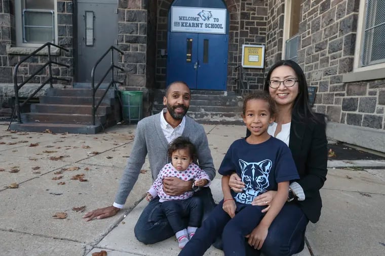 Keiko Glover and her husband Dan pose with their daughters, Maya, age 7, and Hanna, age 1, in front of the General Philip Kearny School at 6th and Fairmount streets.