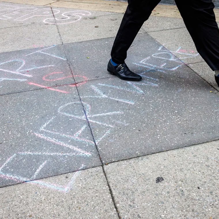 Art is Everywhere is written with chalk on the sidewalk outside the University of the Arts at S. Broad Street and Pine. Students gathered on campus protesting the closure of their school.