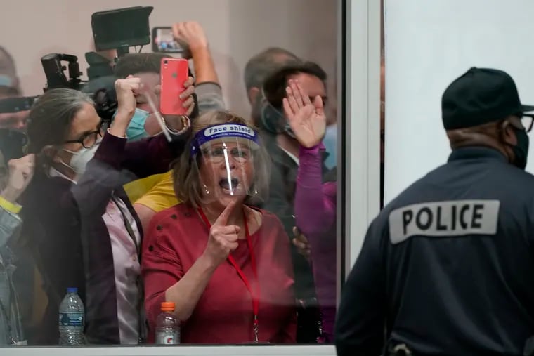 Election challengers yell as they look through the windows of the central counting board as police were helping to keep additional challengers from entering due to overcrowding.