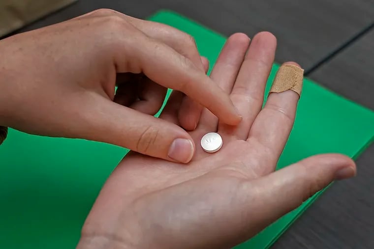 A patient prepares to take the first of two combination pills, mifepristone, for a medication abortion during a visit to a clinic in Kansas City, Kan., on Oct. 12, 2022.