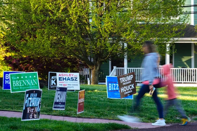 A voter and child walk past campaign signs posted outside of a polling site in Doylestown.