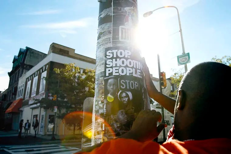 Terry Starks of Philadelphia Ceasefire tapes a poster to a pole near the scene of the subway shooting Wednesday, September 19, 2012. At least one teen was arrested. DAVID MAIALETTI / Staff Photographer