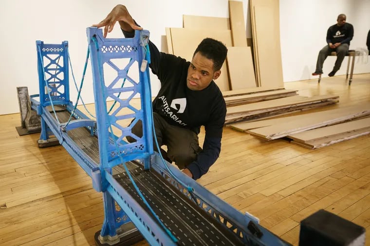 Kambel Smith makes final adjustments on his sculpture of the Benjamin Franklin Bridge in preparation for  his art show at the Fleisher/Ollman Gallery in Center City beginning Thursday.