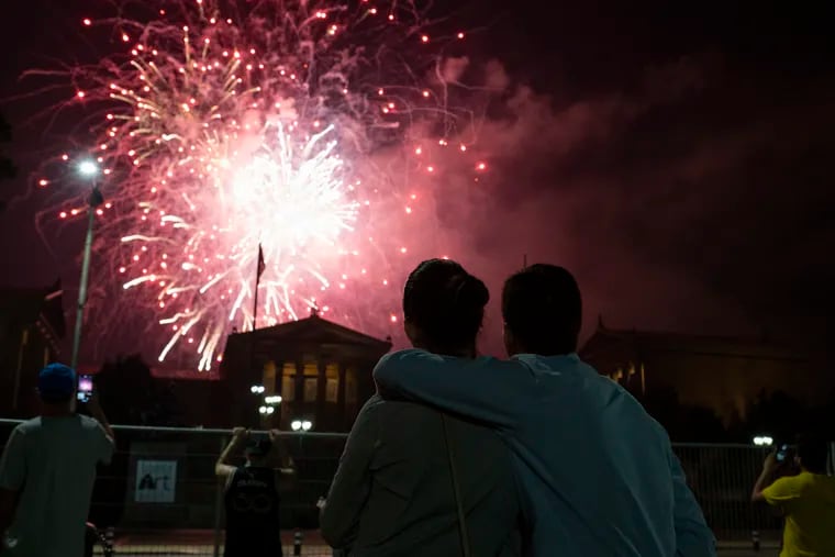 A couple puts their arms around each other as they watch the fireworks over the Philadelphia Museum of Art on July 4, 2023.