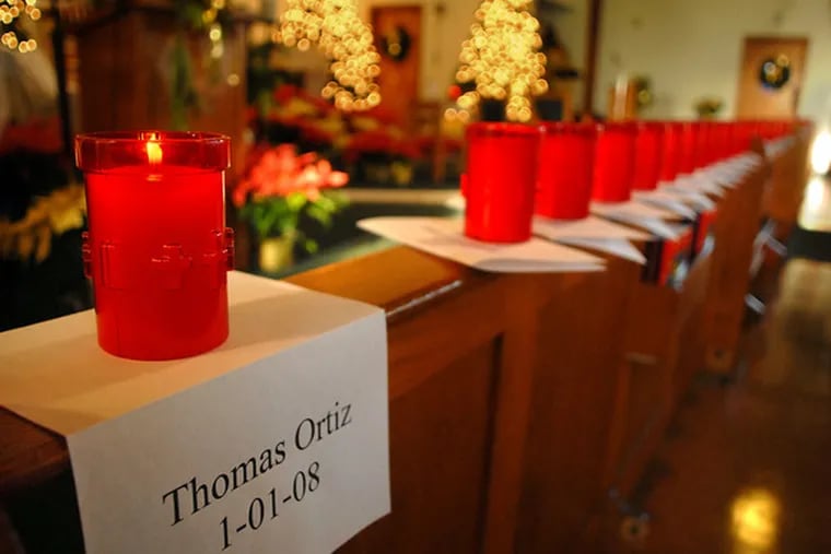 Scores of votive candles, left, were lighted to the memories of the 55 people who died violent deaths in Camden during the year. Their names were inscribed on a ceremonial scroll, right, placed on the altar of St. Joan of Arc Roman Catholic Church.