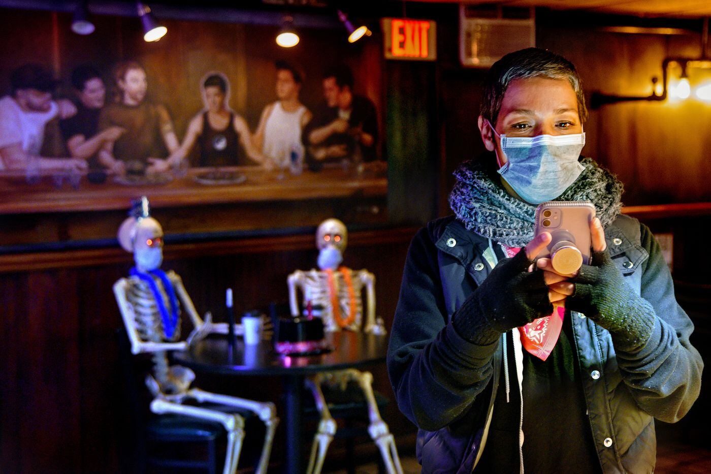 Danielle Renzulli, owner of 12 Steps Down at 9th & Christian, poses at the bar while on Instagram, which was essential to the bar's pandemic survival strategy. That's Renzulli in the center of the painting in rear by Philadelphia artist Tessa Meier. 